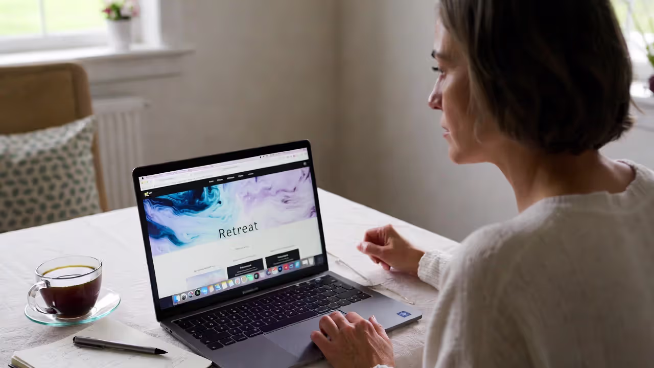 Woman comparing wellness retreat options on laptop at home