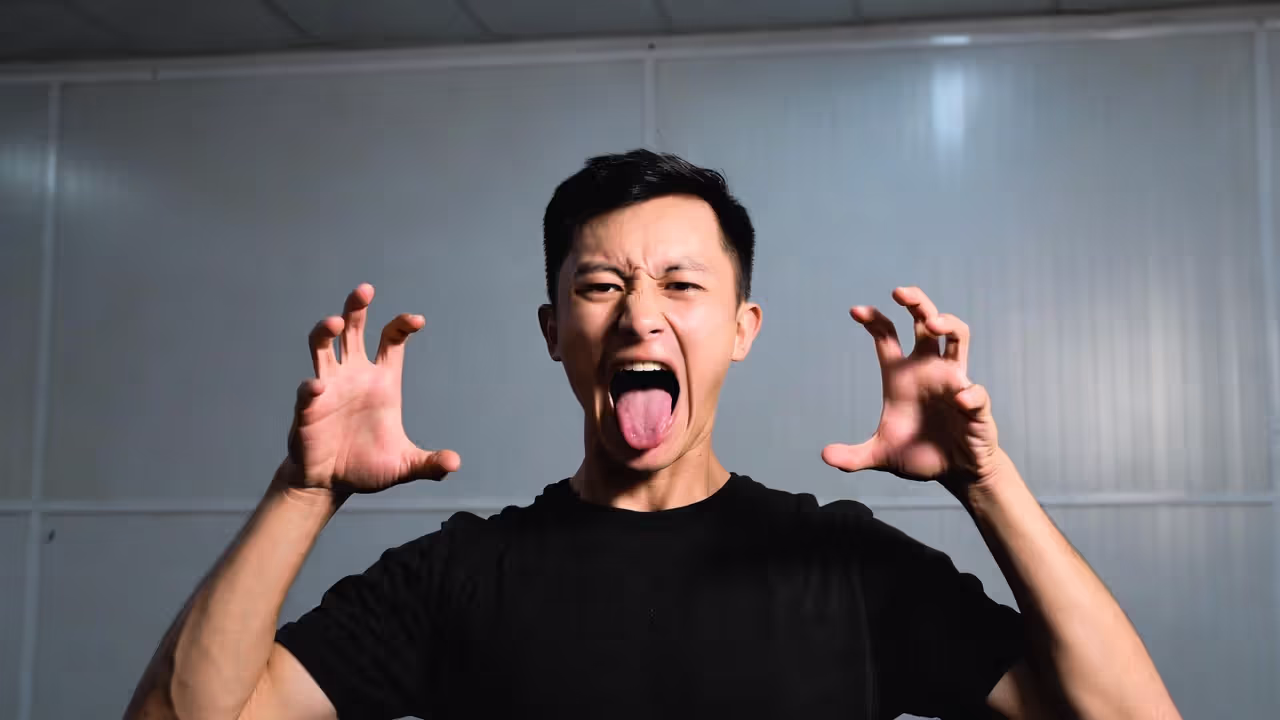 Person performing the lion laughter exercise with tongue extended and hands raised.