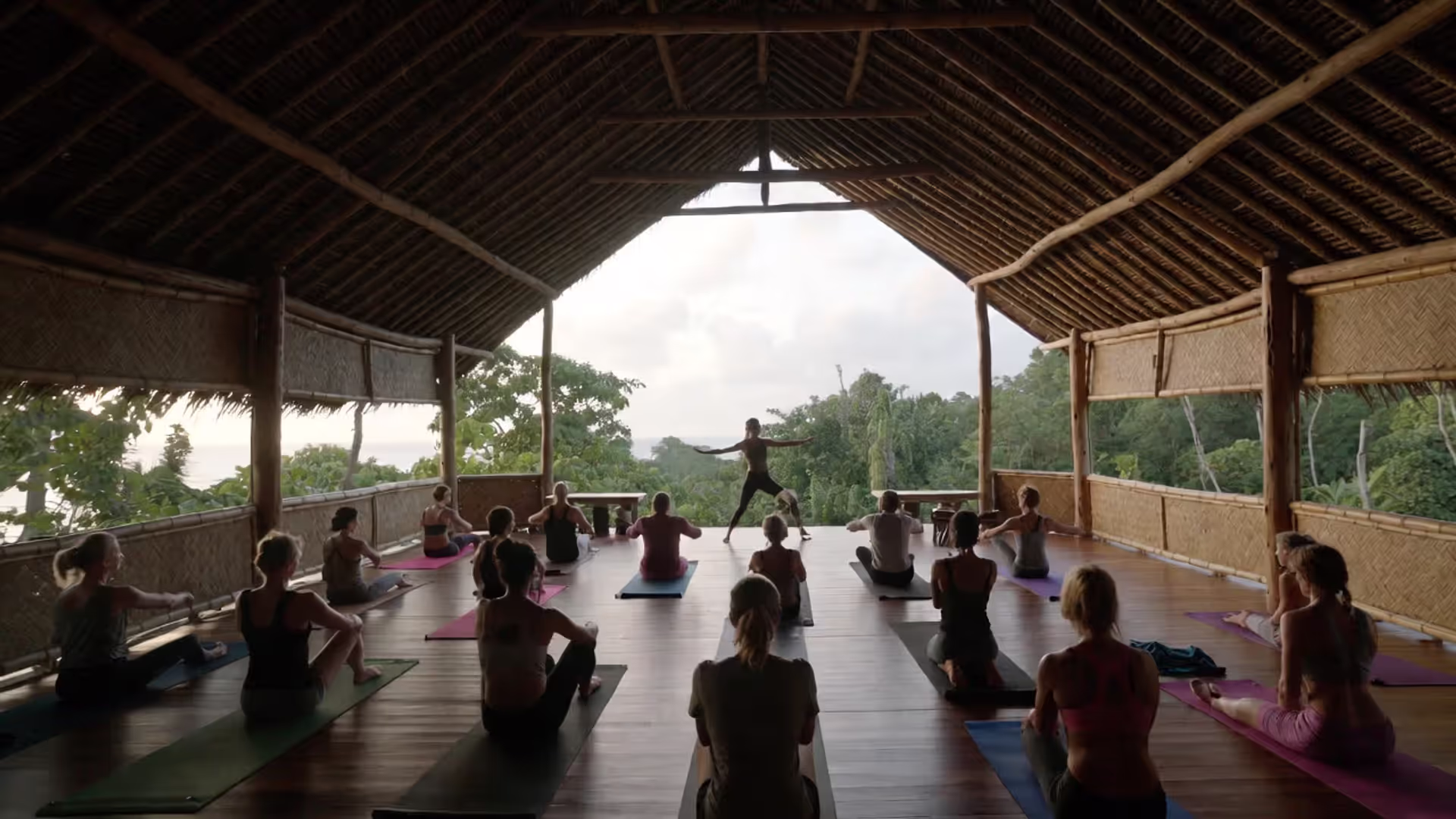 Yoga teacher training group practicing in an open-air pavilion at a tropical retreat center.