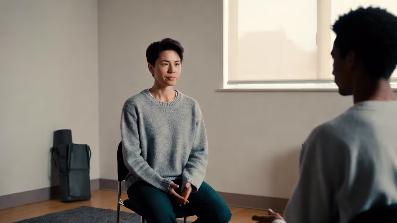 Person in a therapy session with a yoga mat bag nearby, showing yoga as a complement to professional care.